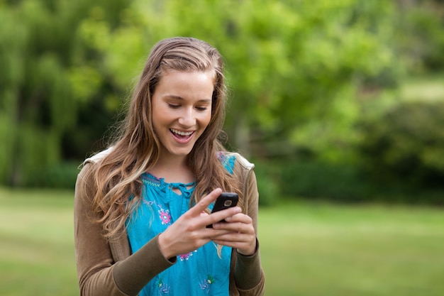 Feliz, menina adolescente, recebendo, um, texto, ligado, dela, telefone móvel