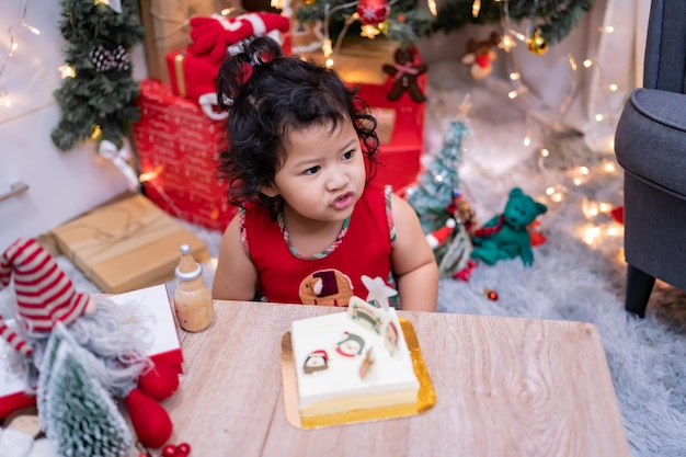 Feliz menina asiática com bolo de Natal em casa nas férias de inverno com a família.