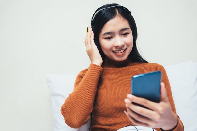 Feliz menina asiática com fones de ouvido, ouvindo música.