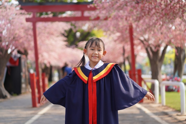 Feliz menina asiática na formatura. sob a flor da árvore sakura