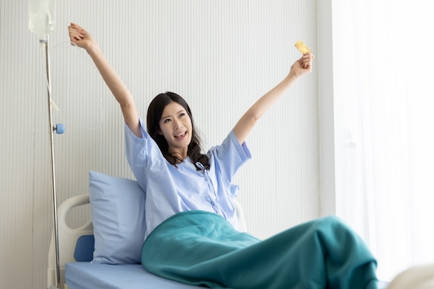 Foto feliz menina asiática numa cama de hospital com cartão de crédito