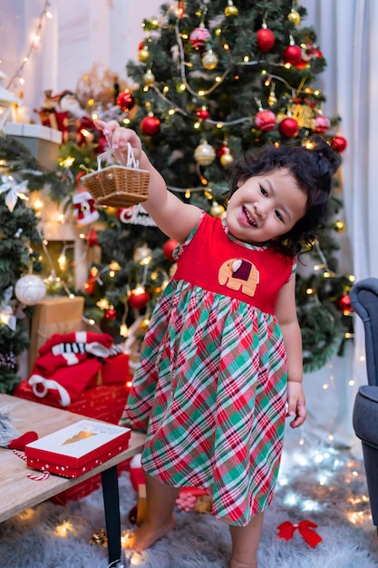 Feliz menina asiática se divertir no dia de Natal. Criança com pai com decoração de árvore de Natal em casa de férias.