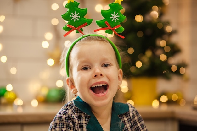 Feliz menina bonita de pijama preparando a massa para biscoitos de ano novo para celebrar o natal.