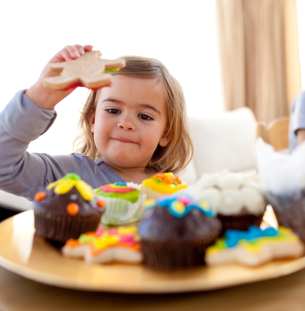 Feliz menina comendo confeitaria em casa