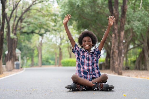 Feliz menino afro-americano levantou a mão depois de jogar patins na estrada em par