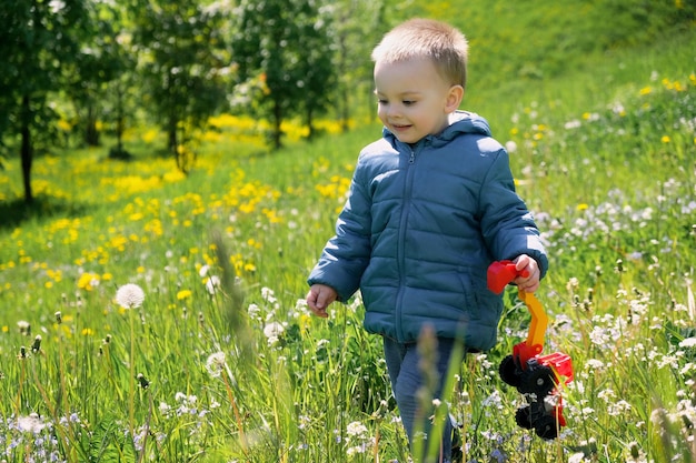 Feliz menino ativo andando pelo prado de primavera