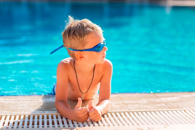 Feliz menino bonitinho em óculos de natação e mergulho na piscina. Conceito de natação para crianças