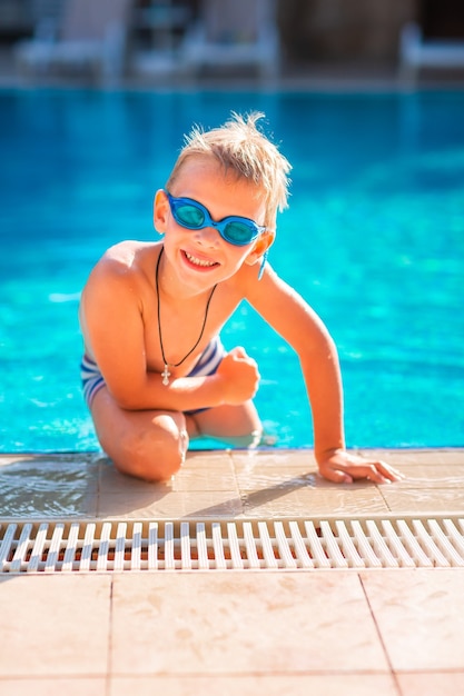 Feliz menino bonitinho em óculos de natação e mergulho na piscina. Conceito de natação para crianças