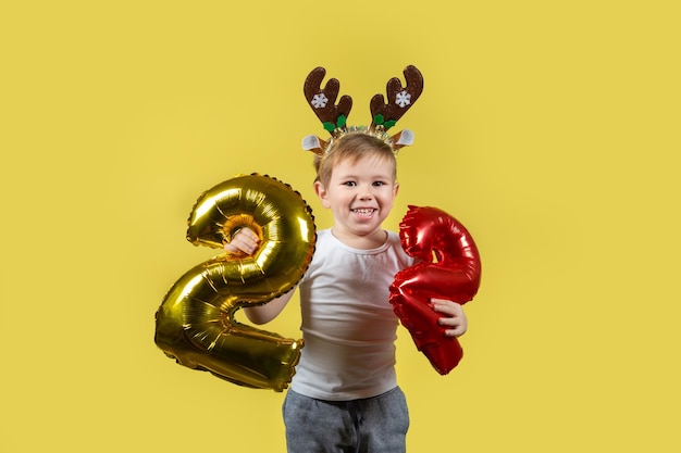 Feliz menino engraçado em fantasia de rena de Natal vermelha com números de balão
