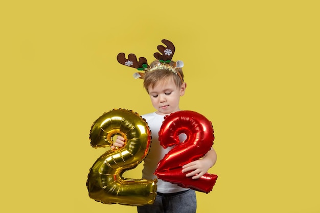 Feliz menino engraçado em fantasia de rena de Natal vermelha com números de balão