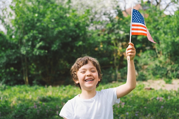 Feliz menino patriótico segurando a bandeira americana EUA comemora 4 de julho Feliz dia da independência