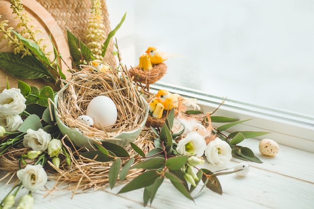 Feliz mesa de pascua. Huevo de Pascua en un nido con decoración floral cerca de la ventana. Huevos de codorniz. Feliz, pascua, concepto