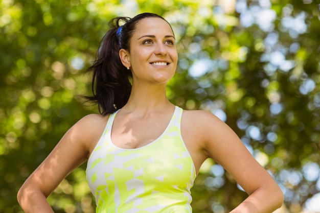 Feliz morena atlética con las manos en las caderas