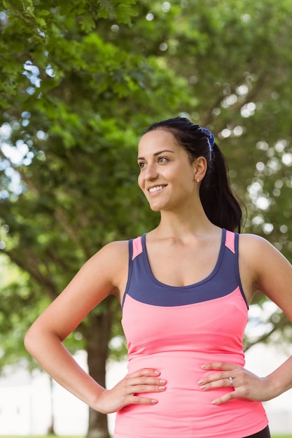 Foto feliz morena en forma con las manos en las caderas