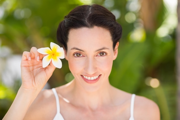 Feliz morena sosteniendo una flor blanca