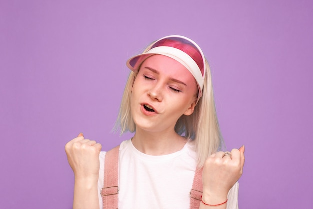 Feliz mujer adolescente con gorra rosa y ropa brillante se regocija