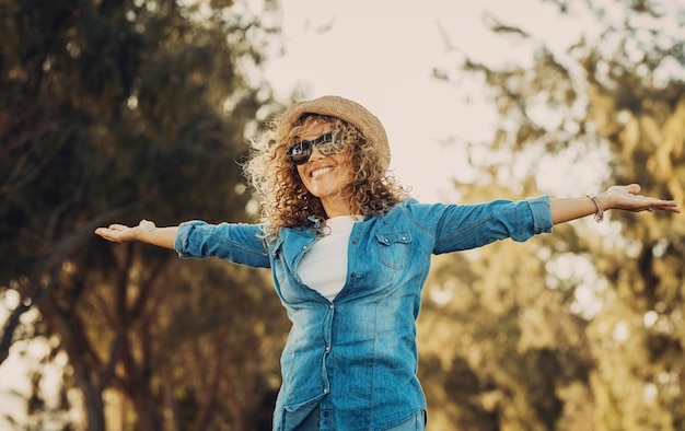 Feliz mujer adulta linda extendiendo los brazos y disfrutando de la actividad de ocio al aire libre Los árboles y la naturaleza en el fondo Concepto de estilo de vida alegre gente femenina Hermosa sonrisa casual joven dama madura