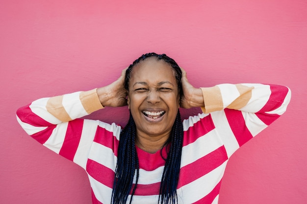 Foto feliz mujer africana senior sonriendo a la cámara con fondo rosa - centrarse en la cara