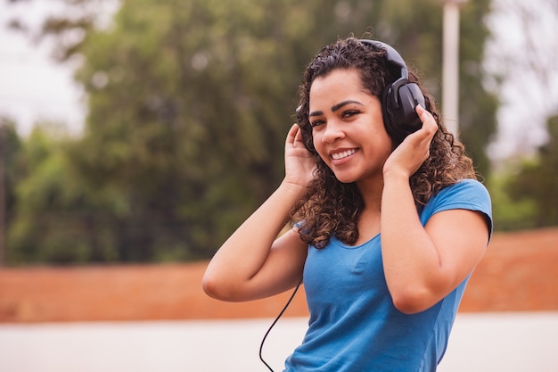 Feliz mujer afro escuchando música en sus auriculares.