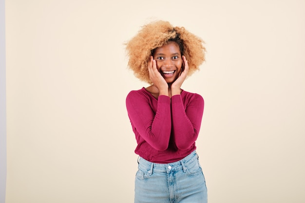 Feliz mujer afro mirando sorprendido y asombrado por la cámara mientras posa sobre un fondo aislado.