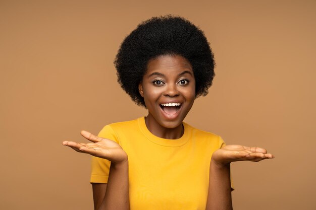 Foto feliz mujer afroamericana carismática con expresión facial feliz sonriendo ampliamente mira a la cámara