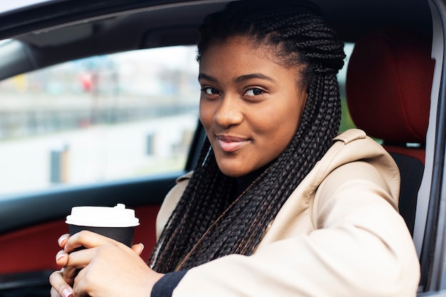 La feliz mujer afroamericana en coche con café