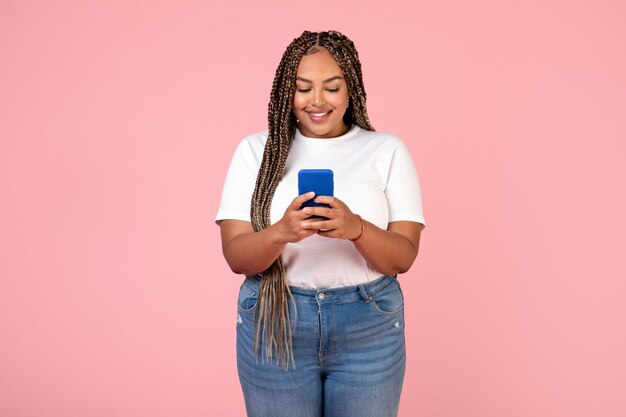 Feliz mujer afroamericana de gran tamaño con smartphone en estudio