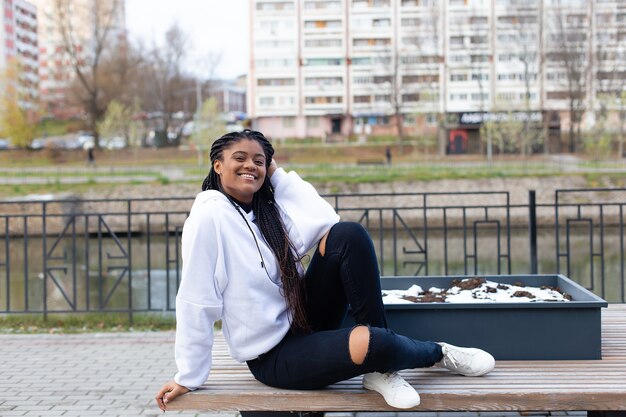 La feliz mujer afroamericana en el parque en un banco