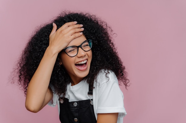 Feliz mujer afroamericana satisfecha toca la frente, se siente con energía y demasiado emotiva