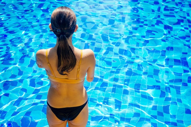 Feliz mujer asiática sin brazos calentándose antes de nadar en la playa tropical salta