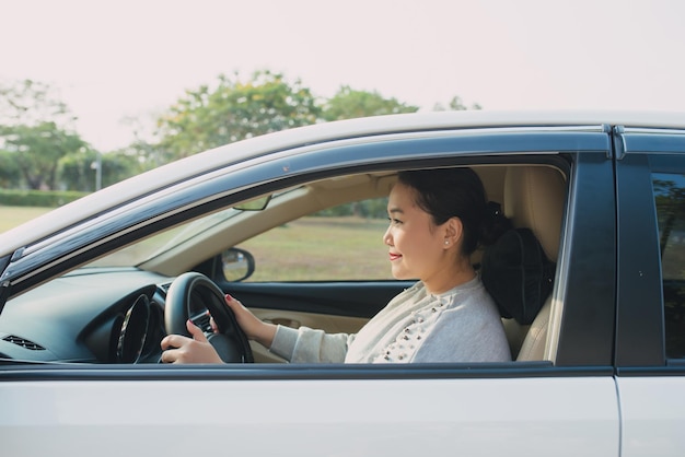 Feliz mujer asiática conduciendo viajes por ella misma.