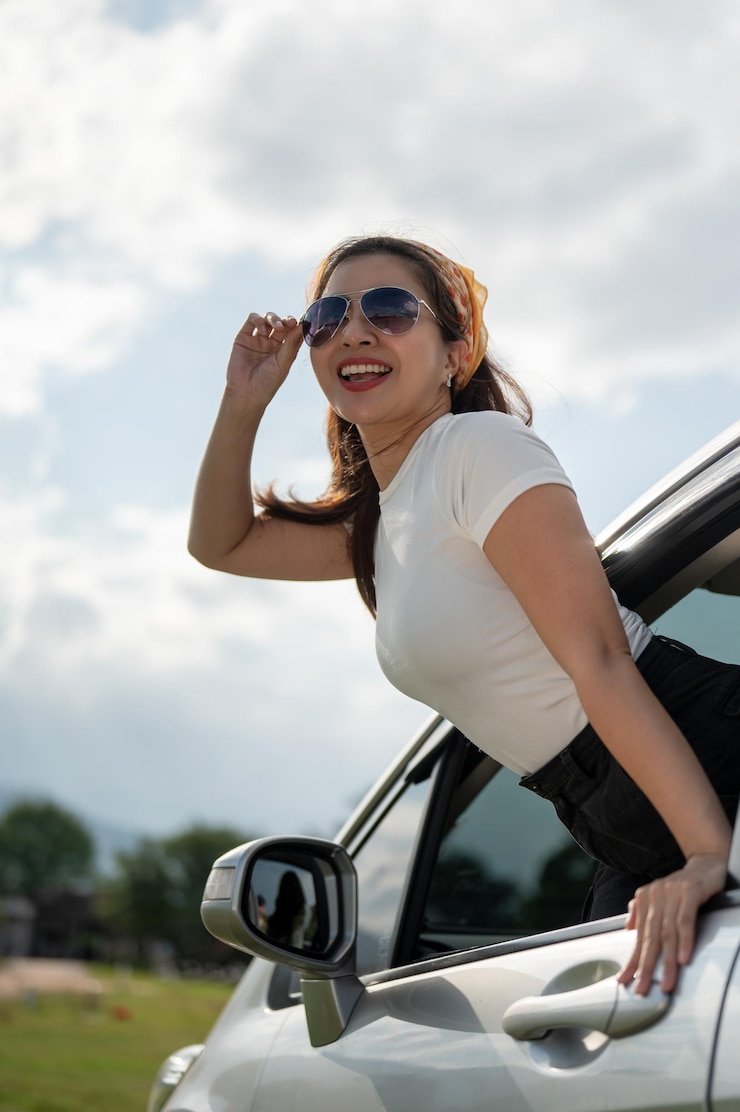 Foto una feliz mujer asiática disfruta del viento fuera del auto y se divierte durante su viaje por carretera