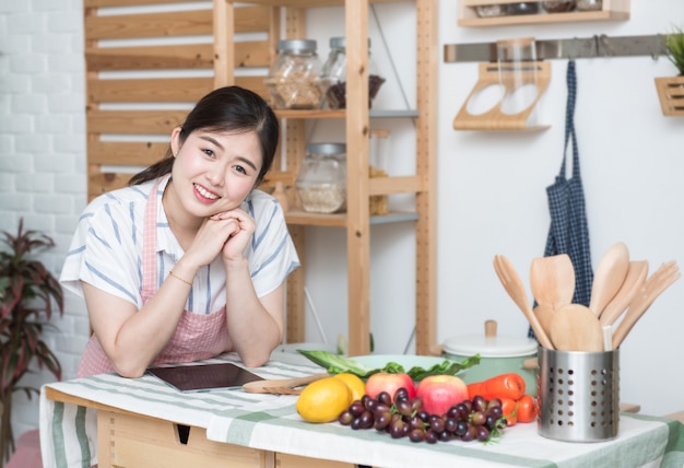 Feliz mujer asiática haciendo receta en la cocina