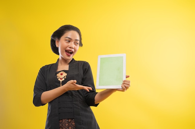 Feliz mujer asiática con kebaya mostrando la pantalla de la tableta