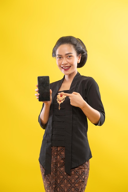 Feliz mujer asiática con kebaya mostrando la pantalla del teléfono