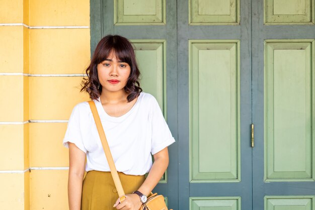 Feliz mujer asiática posando con bolso