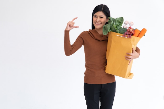 Feliz mujer asiática sonriendo y abra la palma de la mano y lleva una bolsa de compras