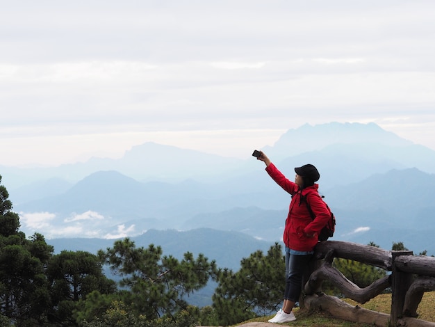 Feliz mujer asiática turista tomando fotografía sobre Mountain View con fondo de niebla