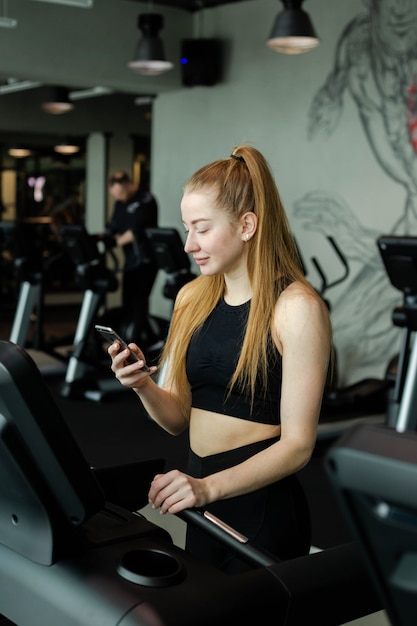 Feliz mujer atlética trotar en cintas de correr en un gimnasio