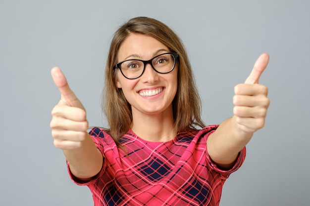 Feliz mujer caucásica vistiendo gress rojo haciendo pulgar arriba signo