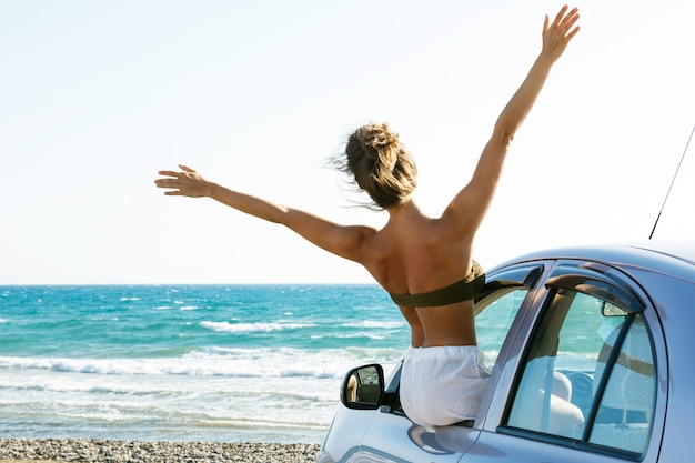 Feliz mujer y coche en la playa