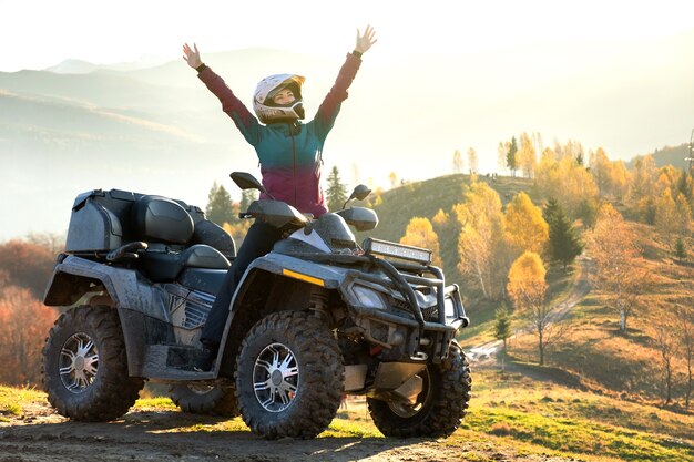 Feliz mujer conductora en casco protector disfrutando de la conducción todoterreno en ATV quad moto