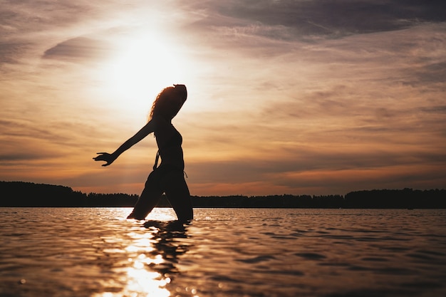 Feliz mujer despreocupada disfrutando de la hermosa puesta de sol en la playa