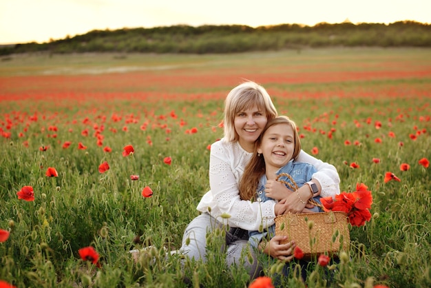 Feliz mujer e hija en campo de amapolas