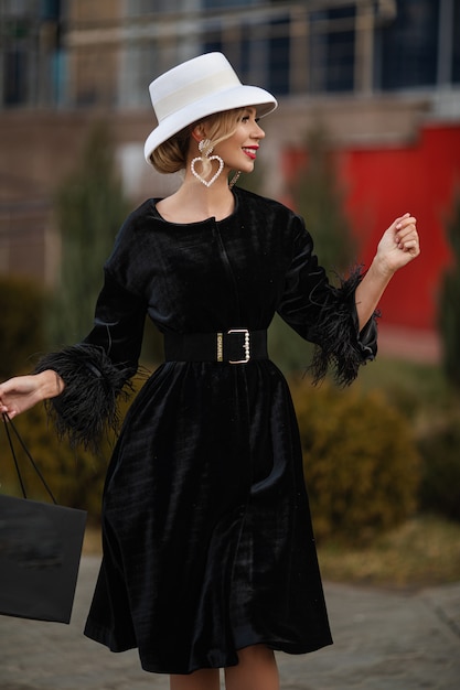 Feliz mujer elegante con flores posando al aire libre