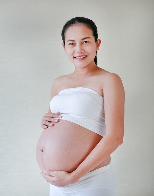 Feliz mujer embarazada sostiene su gran barriga.