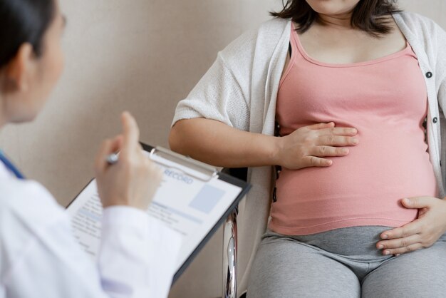 Feliz mujer embarazada visita al médico ginecólogo en el hospital