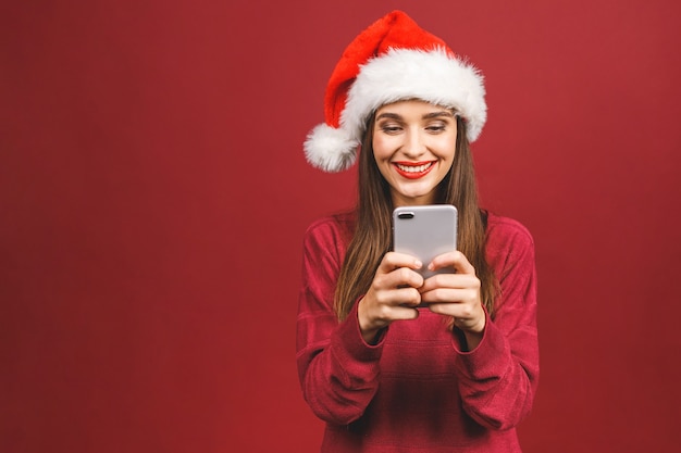 Feliz mujer emocionada con sombrero rojo de santa claus con teléfono móvil