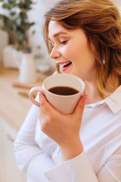 Feliz mujer encantada de estar de buen humor mientras disfruta de su sabroso té