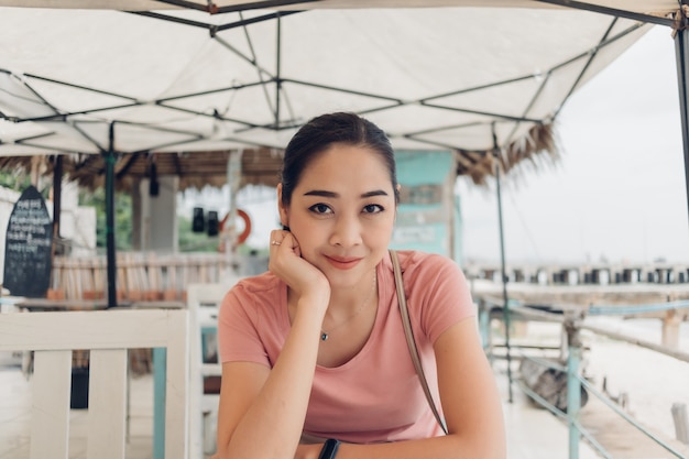 Feliz mujer está sentada en el restaurante en la playa.